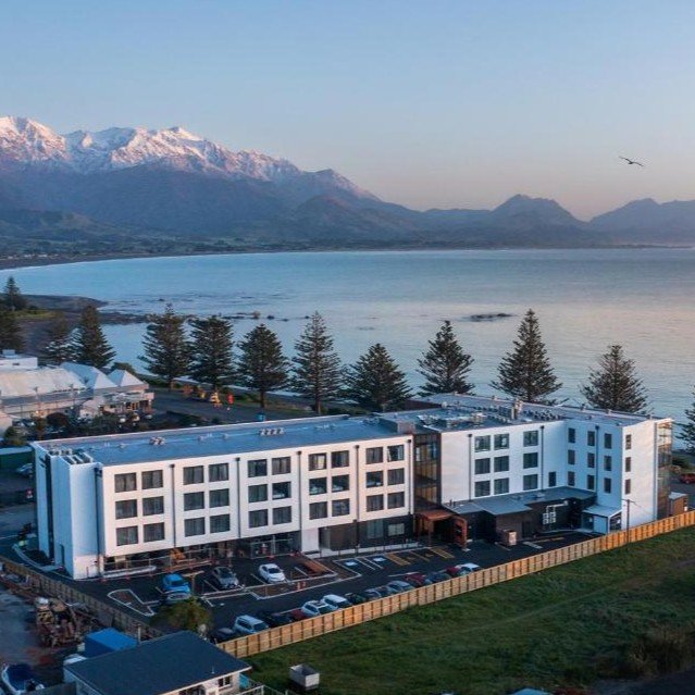View of Sudima Hotel Kaikoura with snow-capped mountains and bay in background